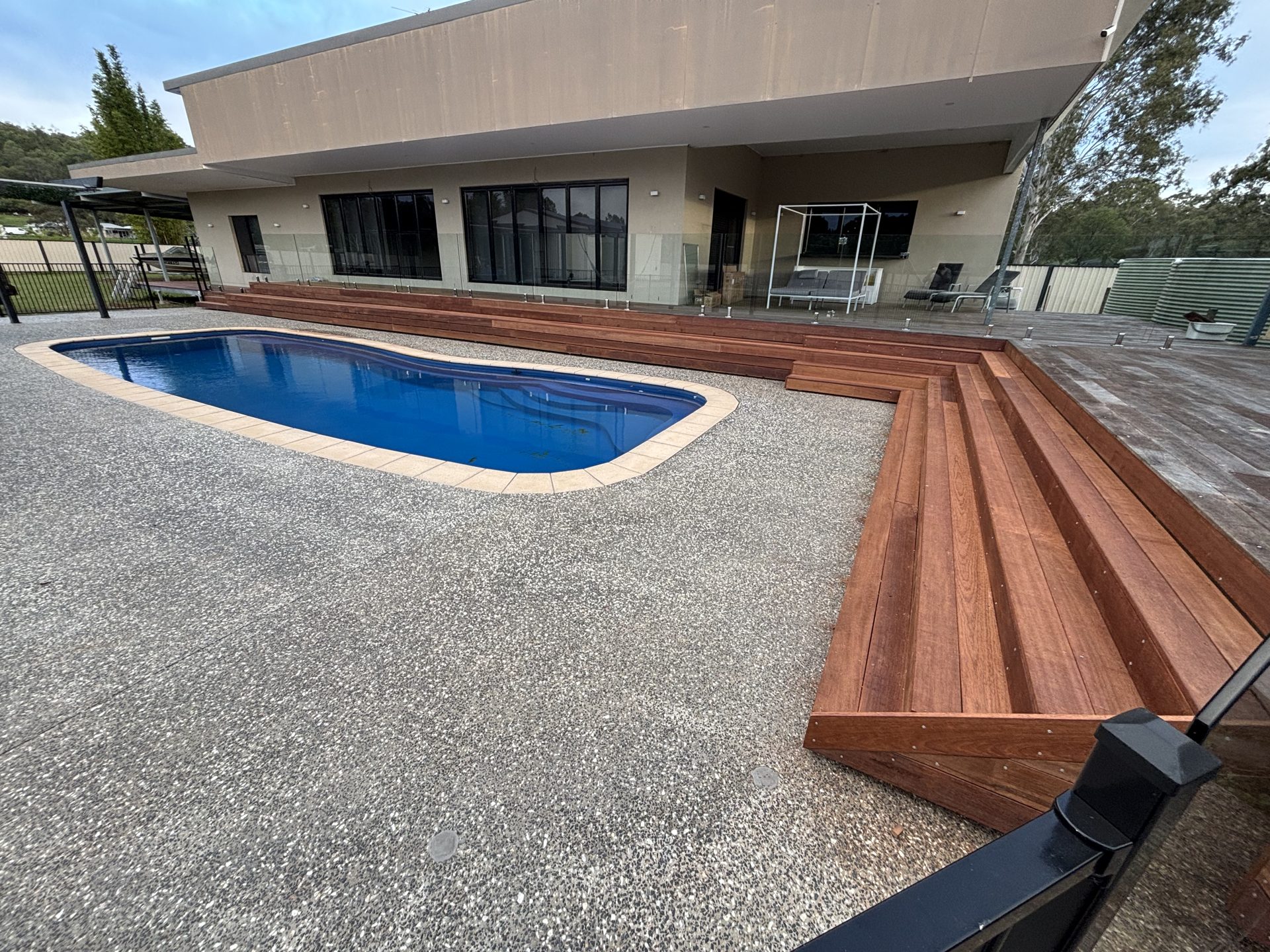 Poolside hardwood staircase and deck by Curtain Constructions